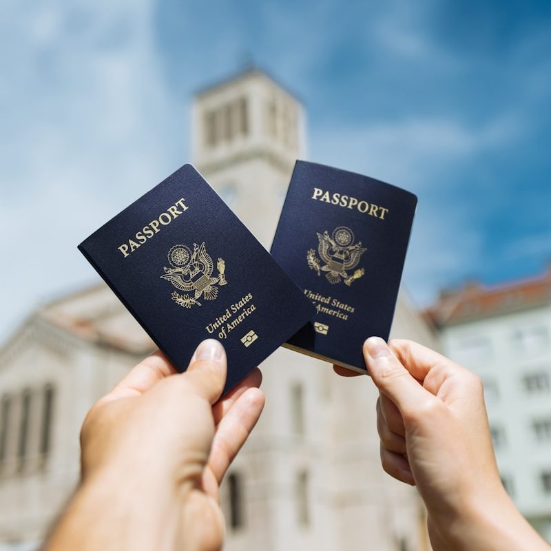 two people holding up two passports in front of a building